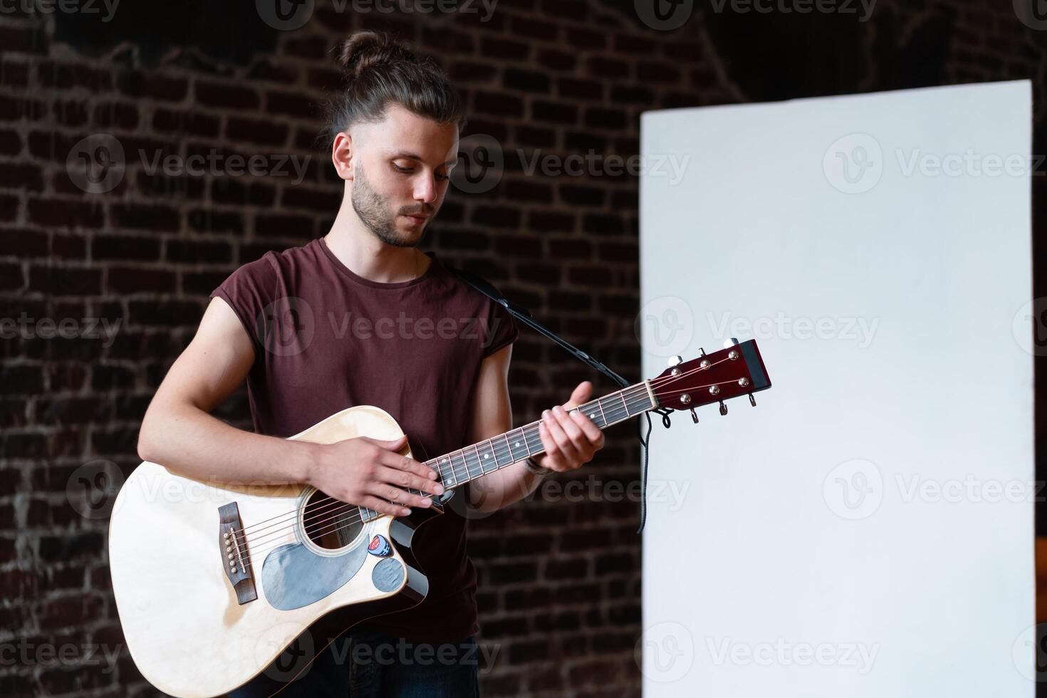 homem com acústico guitarra em pé perto quadro branco música escola conceito foto