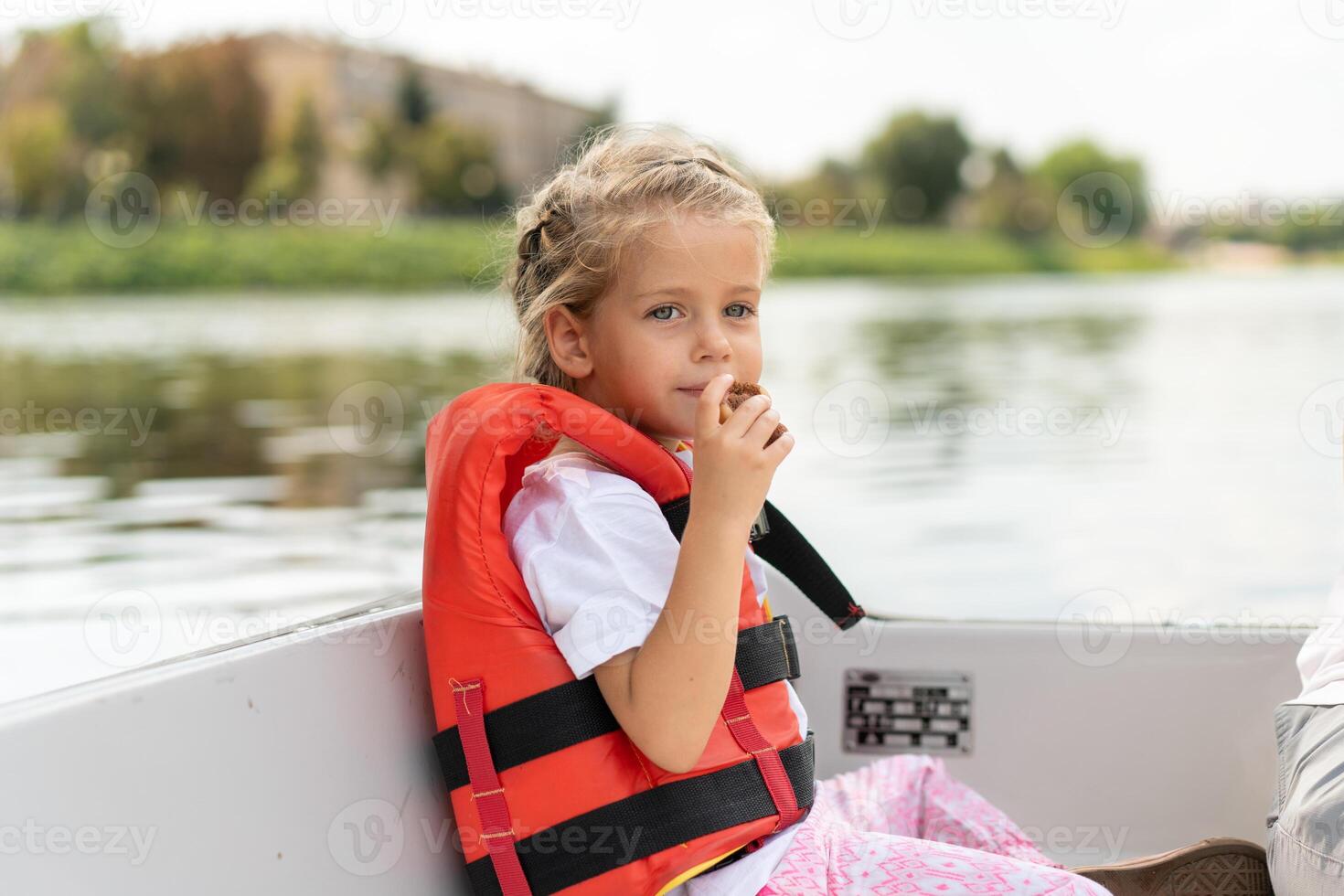 pequeno menina vestido vida colete passeio prazer barco em cidade rio ensolarado verão dia caucasiano fêmea criança natação em barco foto