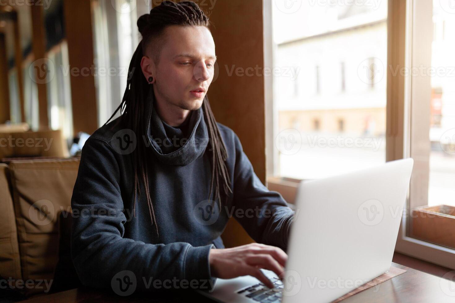 jovem homem de negocios com dreadlock tendo fazendo dele trabalhos dentro cafeteria com computador portátil. foto