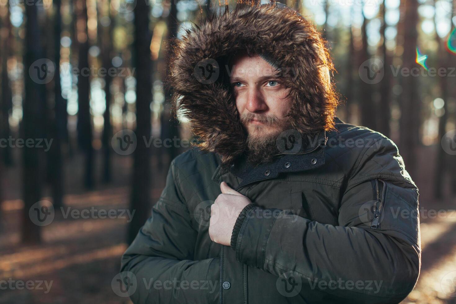 fechar acima retrato do uma barbudo hipster turista dentro cinzento de capuz homem dentro a luz solar foto