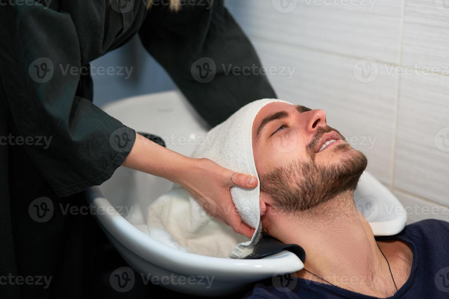 mulher aplicando xampu massageando cabelo cliente homem lavar cabelo dentro beleza salão cabeleireiro lavando cabelo. feliz caucasiano cara apreciar serviço dentro barbearia foto