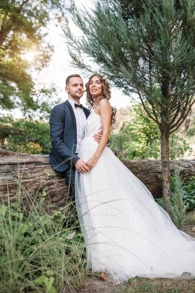 noiva e noivo às Casamento dia caminhando ao ar livre em verão natureza. nupcial casal, feliz recém-casado mulher e homem abraçando dentro verde parque. amoroso Casamento casal ar livre. noiva e noivo foto