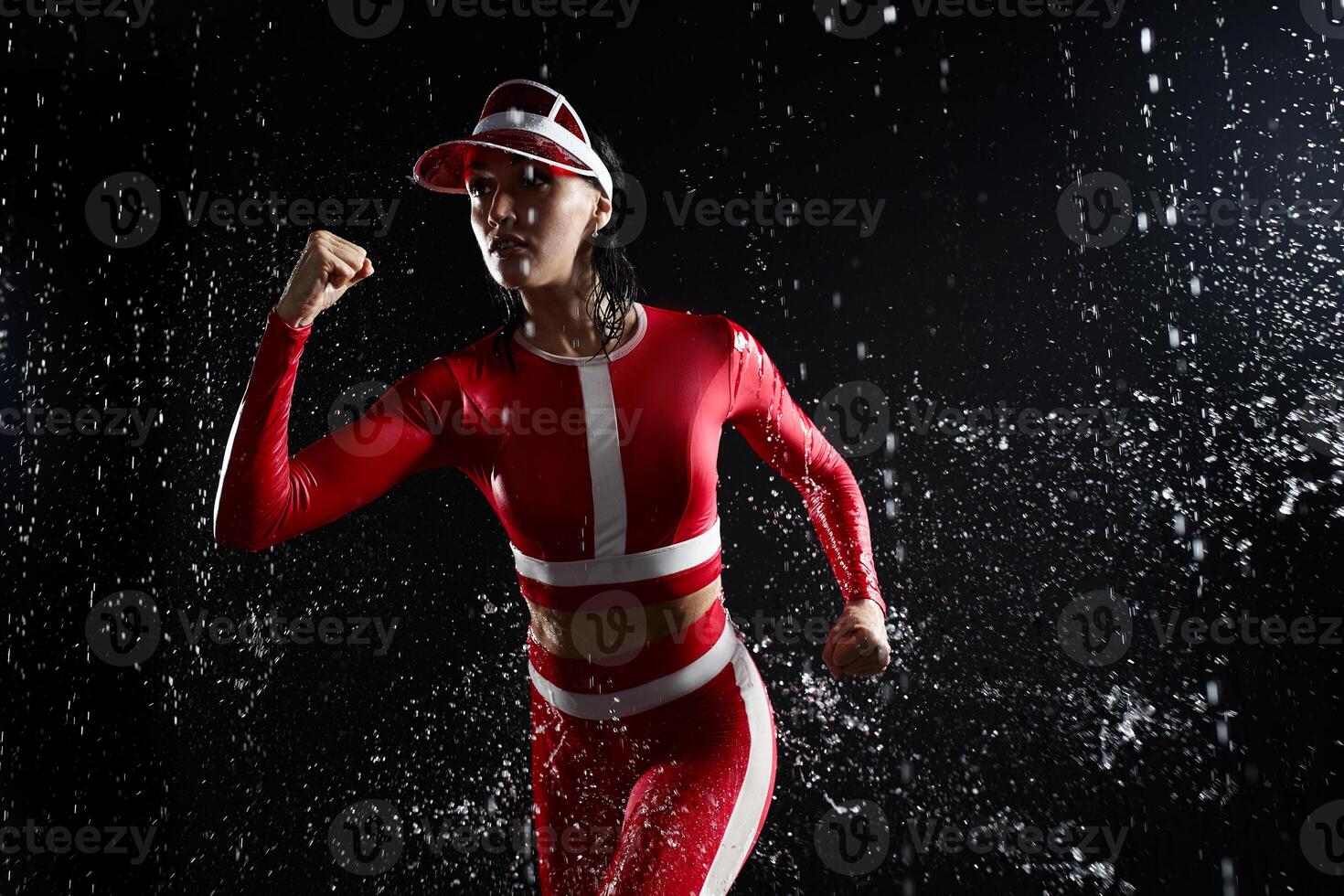 lindo jovem menina dentro roupa de esporte correndo dentro aqua estúdio. gotas do água espalhar sobre dela ginástica corpo. a perfeito figura em a fundo do água salpicos. mau clima para esporte foto