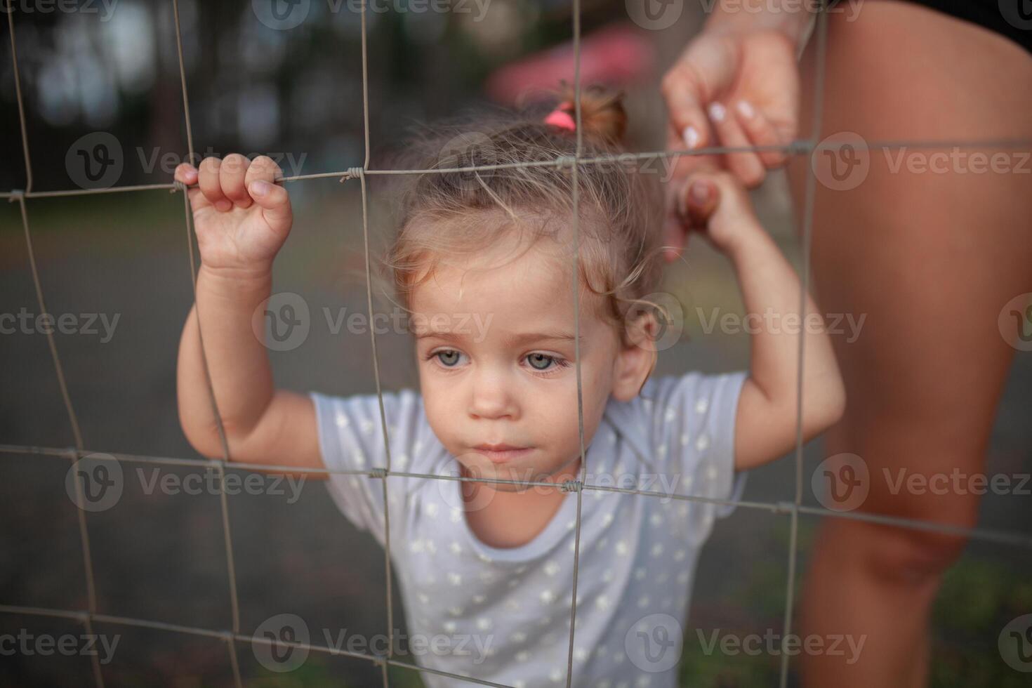 tonificado retrato do triste pequeno menina parece através fio cerca foto