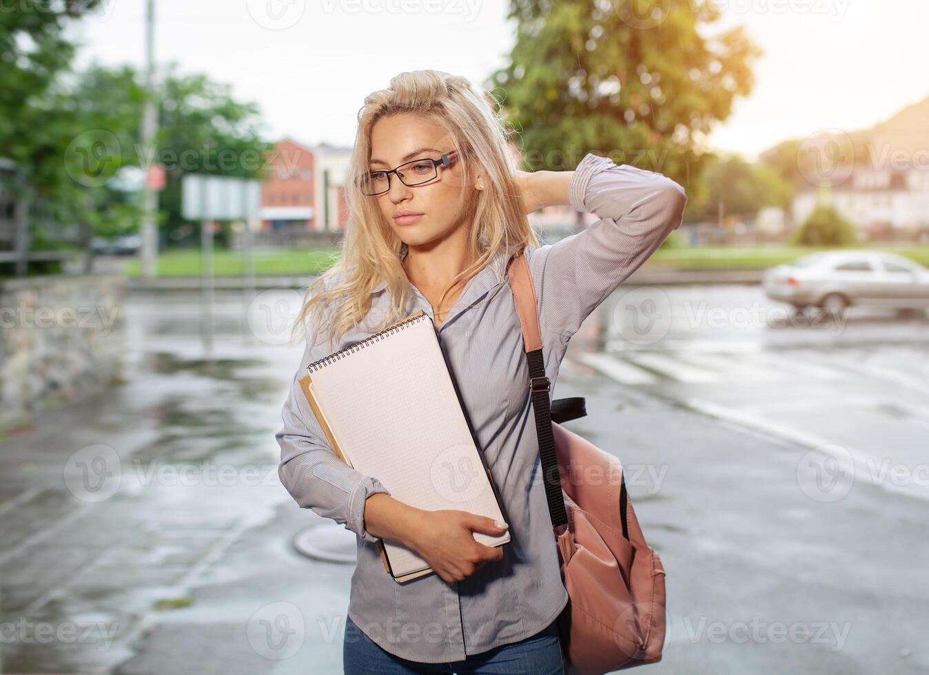 entusiasmado sério lindo jovem menina segurando pilha do livros em pé perto campus estilo de vida positividade acadêmico graduando universidade escola foto