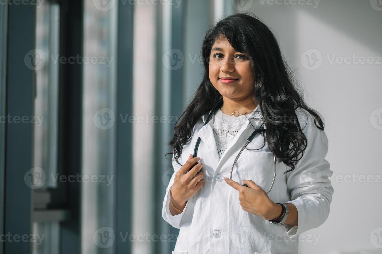 indiano mulher médico ou enfermeira às a clínica dentro prática. fêmea médico dentro uma branco casaco com uma estetoscópio foto