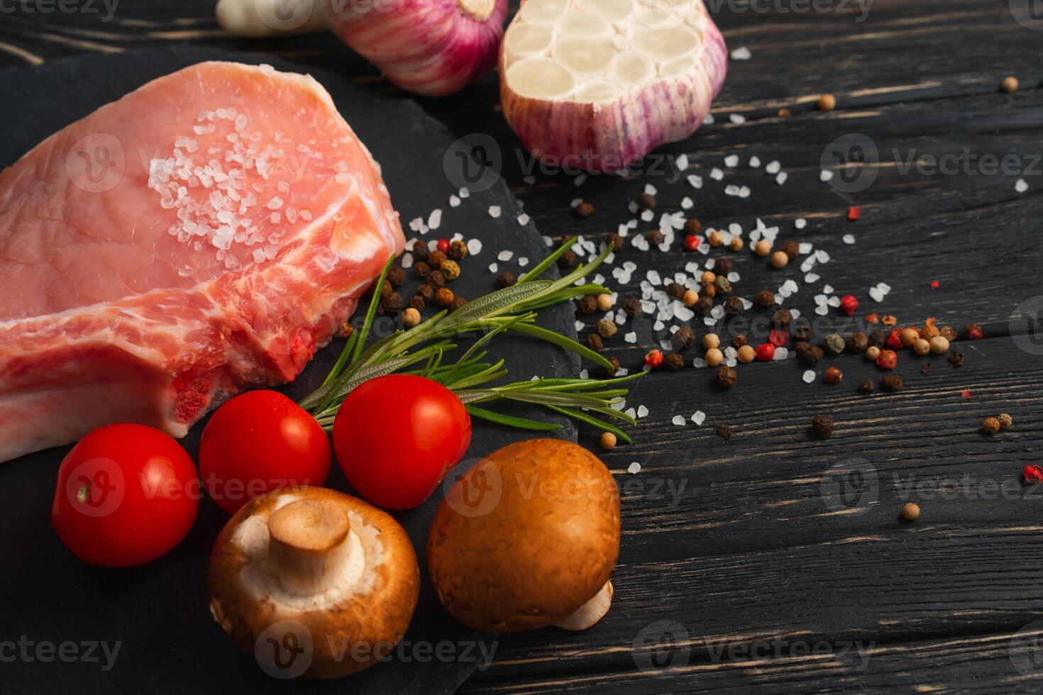 topo Visão do 1 peças cru carne de porco Picar bifes com cereja tomates cogumelo cogumelos em uma Preto pedra corte borda. foto