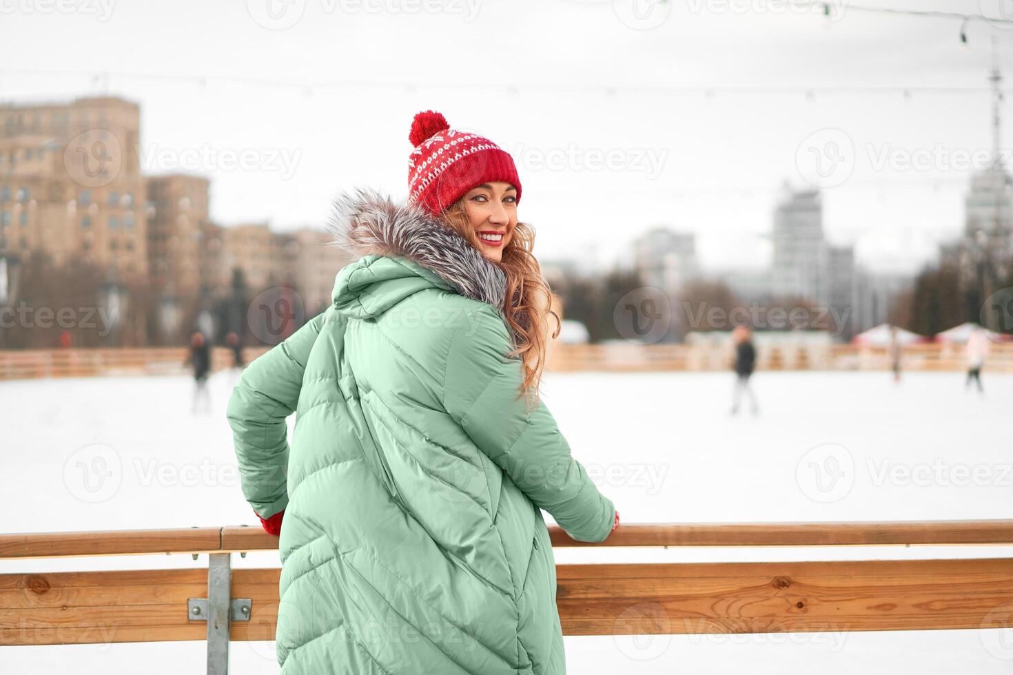 lindo adorável meia idade menina com encaracolado cabelo caloroso inverno jaquetas carrinhos gelo rinque fundo Cidade quadrado. foto