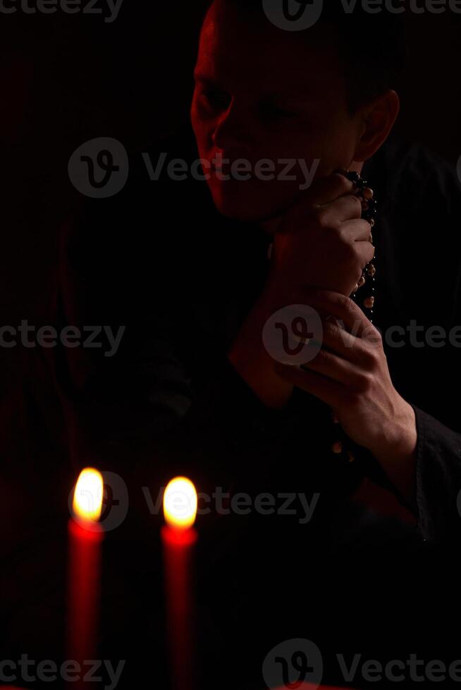 jovem adulto caucasiano católico sacerdote em Sombrio vermelho fundo foto