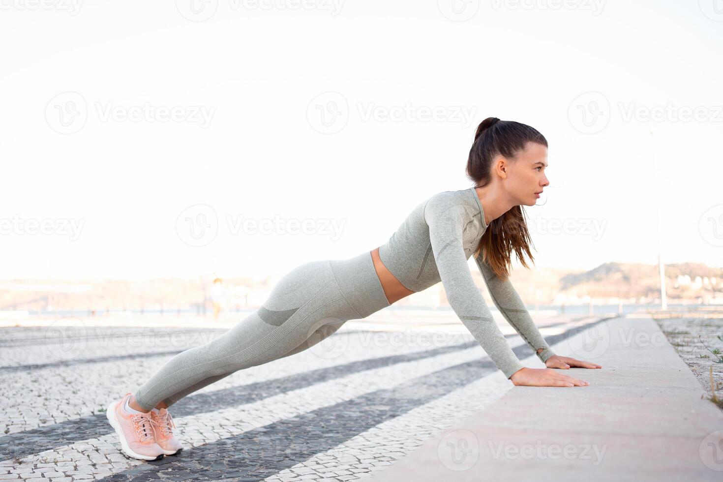 jovem atraente menina atleta dentro roupa de esporte realizando flexões em concreto degrau foto