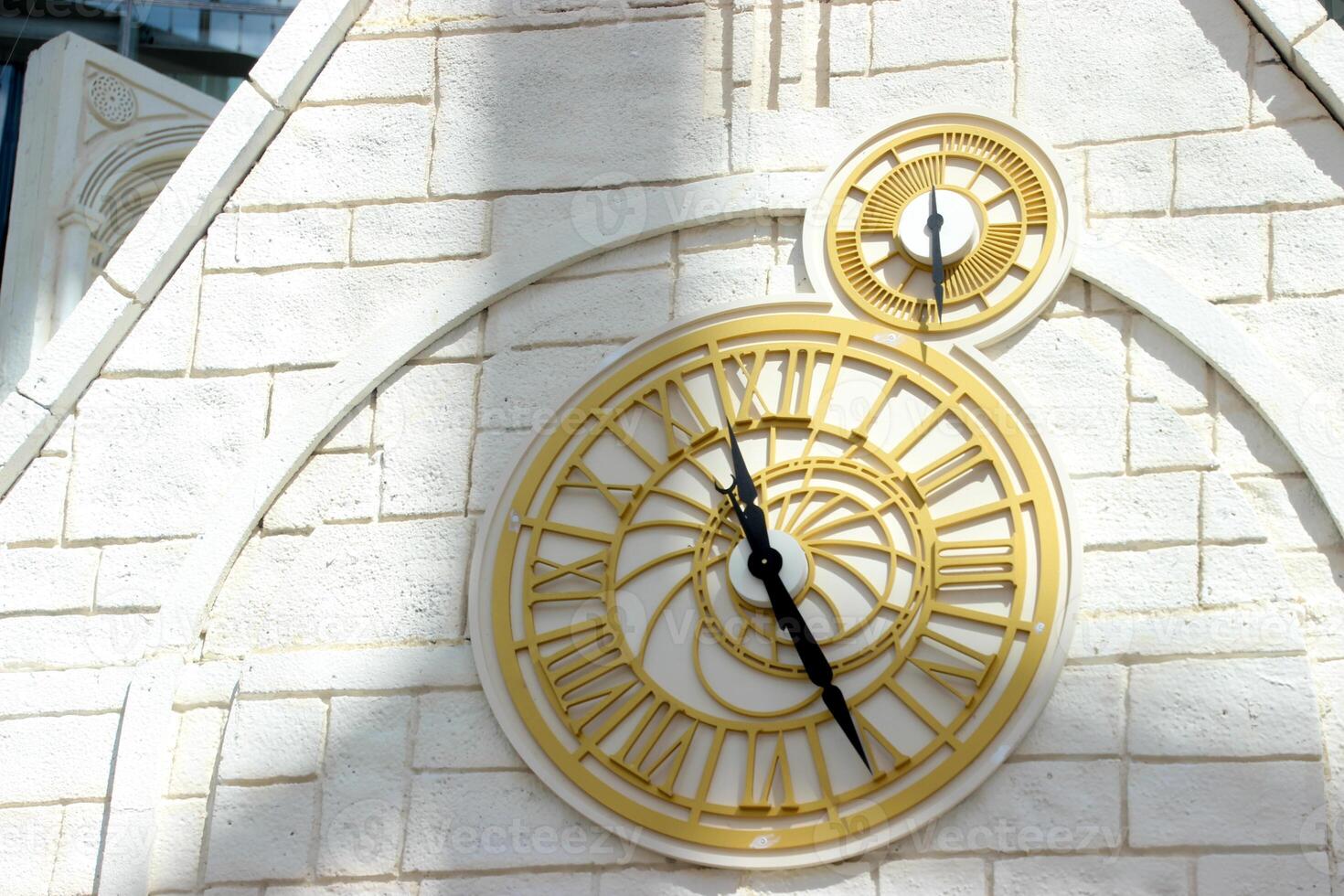 detalhe do a dourado relógio em a branco tijolo torre parede foto