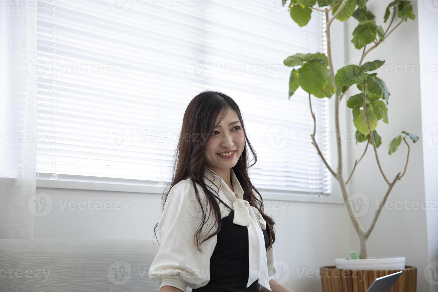 uma relaxado japonês mulher de controlo remoto trabalhos dentro a casa escritório foto