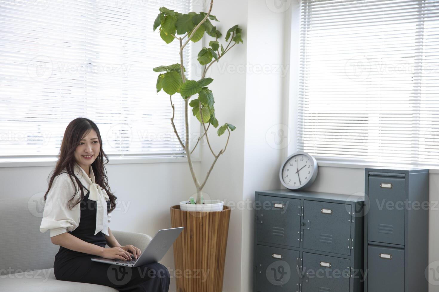 uma japonês mulher verificação Smartphone de controlo remoto trabalhos dentro a casa escritório foto