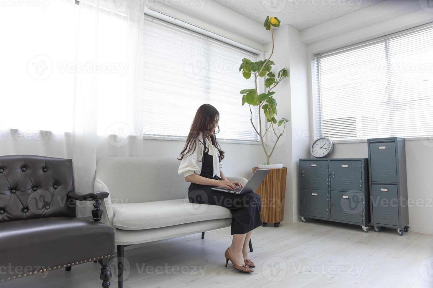 uma japonês mulher verificação Smartphone de controlo remoto trabalhos dentro a casa escritório foto