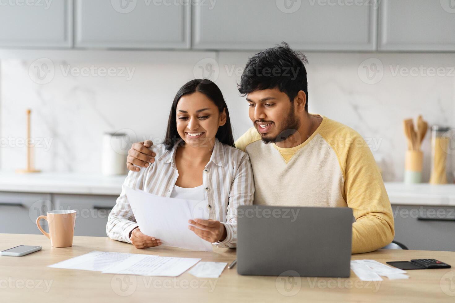 feliz jovem indiano esposas lendo carta a partir de banco, cozinha interior foto