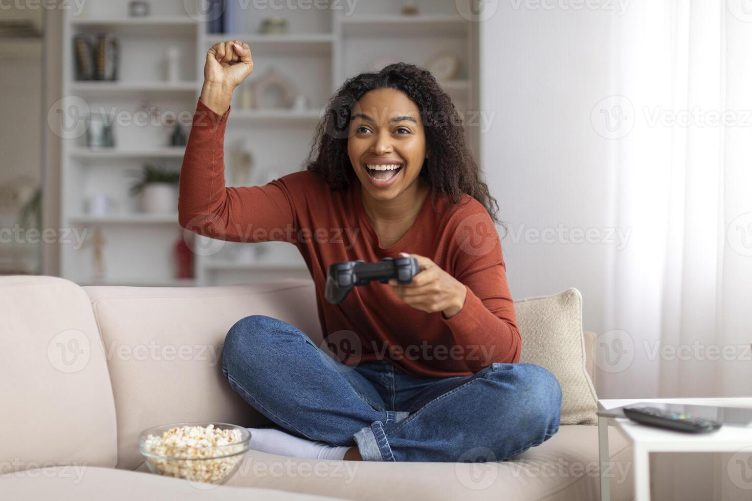 muito feliz jovem Preto mulher a comemorar ganhar enquanto jogando vídeo jogos às casa foto