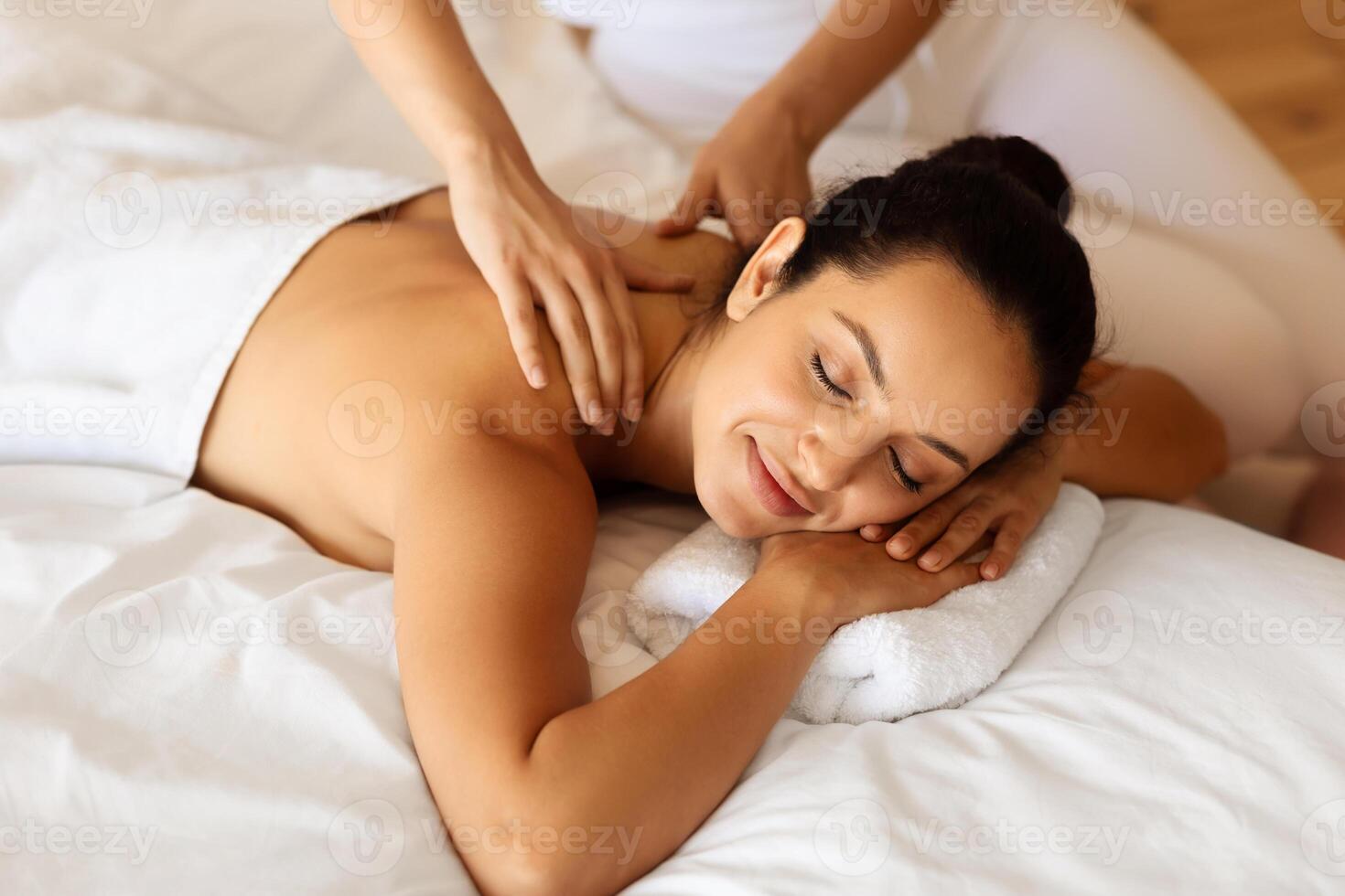 relaxado morena senhora deitado durante relaxante costas massagem dentro spa foto