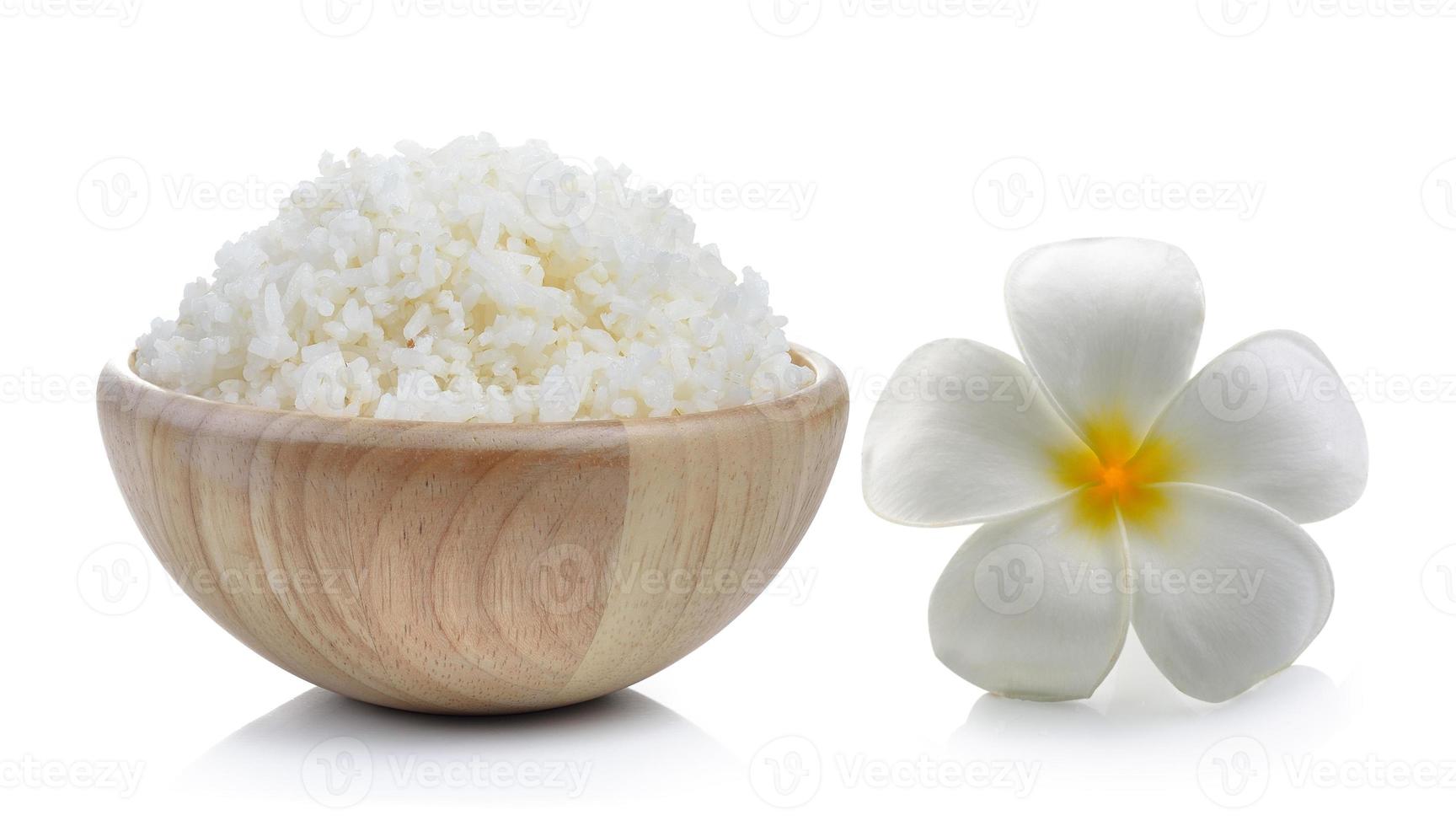 arroz em tigela de madeira e flores de frangipani em fundo branco foto
