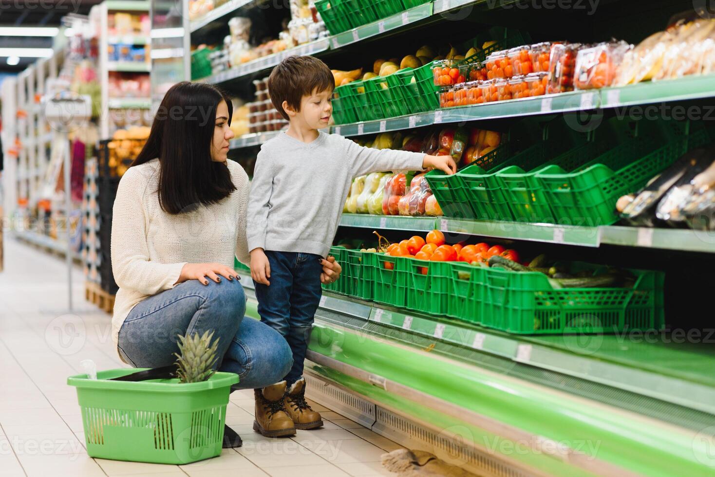 mulher e criança Garoto durante família compras com carrinho às supermercado foto