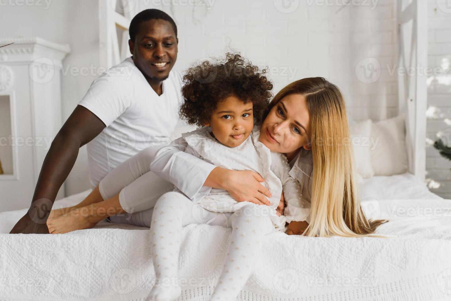 feliz interracial casal com seus pequeno filha às casa foto
