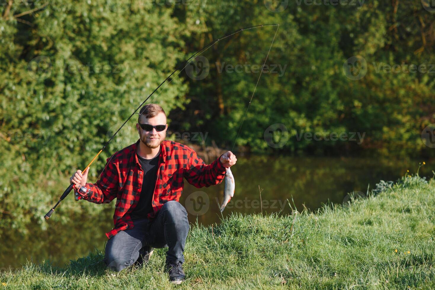 pescador de a rio com uma pegar do peixe. homem pescador detém dentro mão peixe. foto