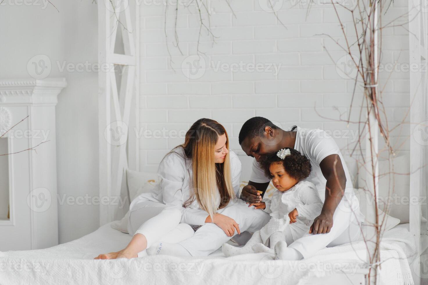 animado multirracial jovem família com pequeno menina criança ter diversão, muito feliz feliz. internacional mãe e Papai jogar com pequeno garota, apreciar final de semana às casa juntos foto