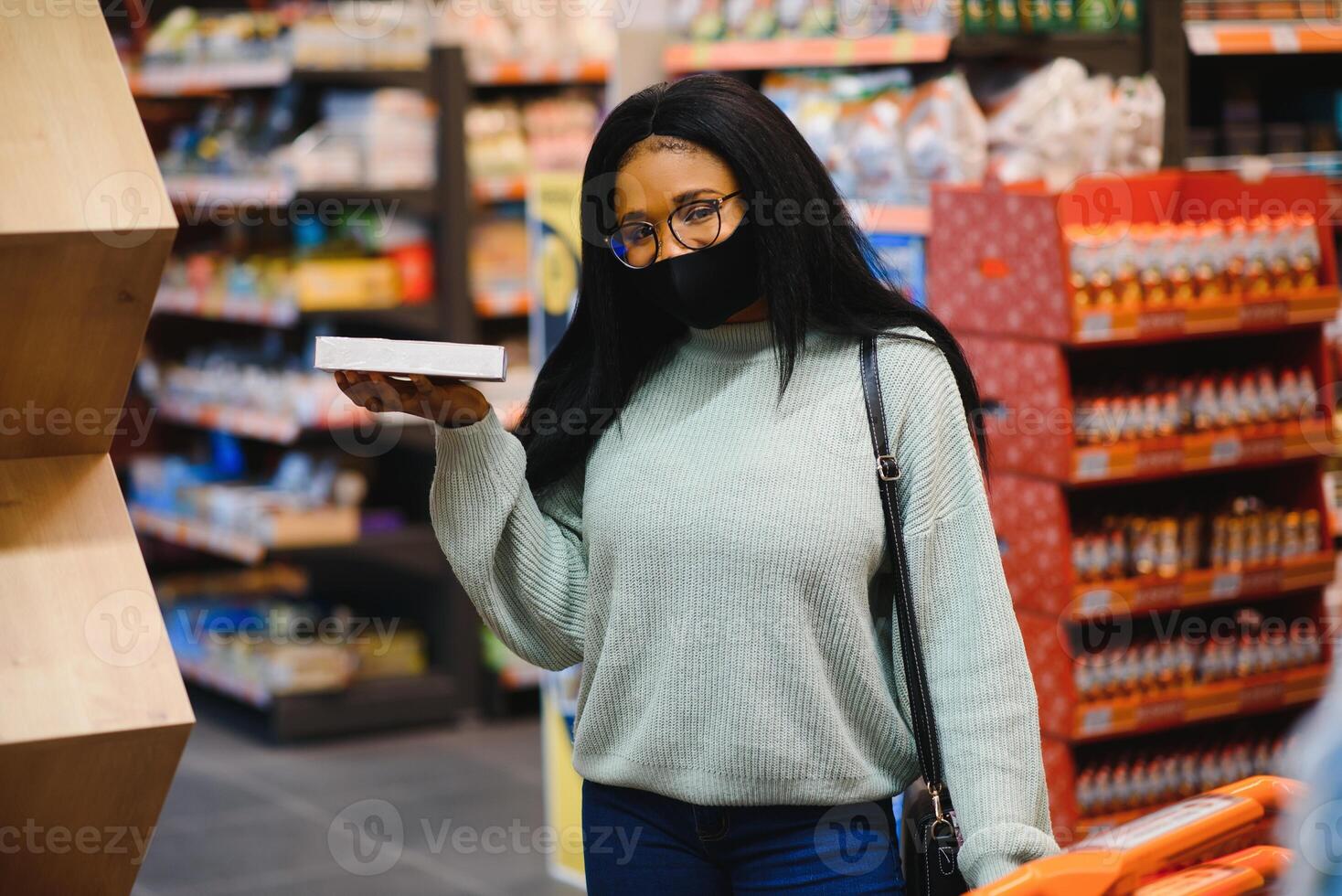 africano mulher vestindo descartável médico mascarar compras dentro supermercado durante coronavírus pandemia surto. epidemia Tempo foto