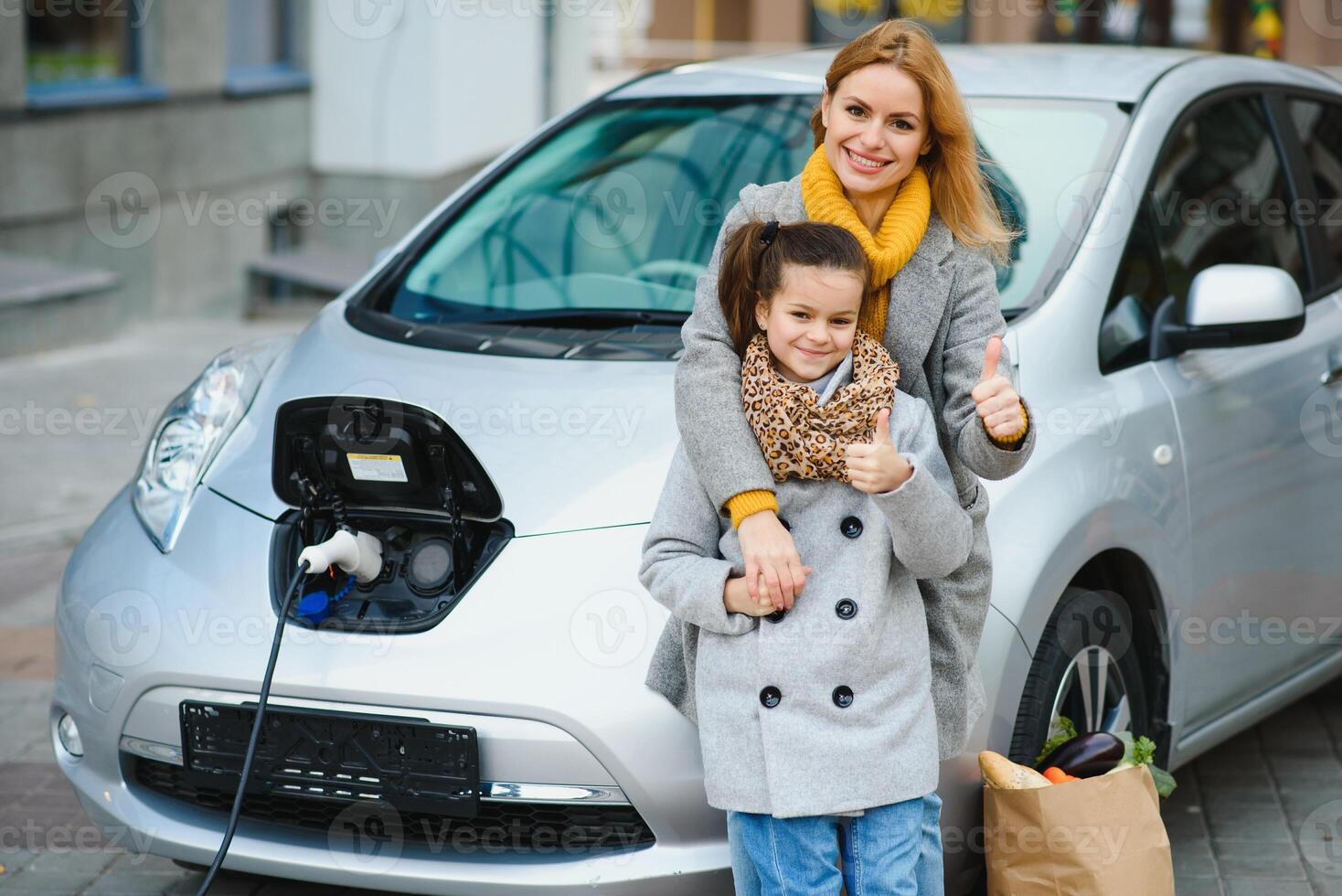 à moda mãe e filha carregar a elétrico carro, e gastar Tempo junto. foto