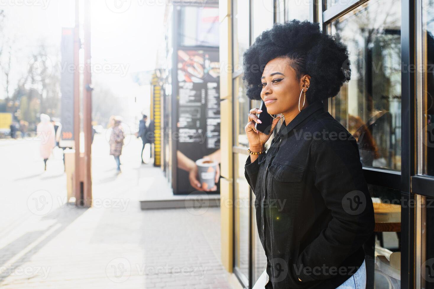 alegre africano mulher usando inteligente telefone ao ar livre foto