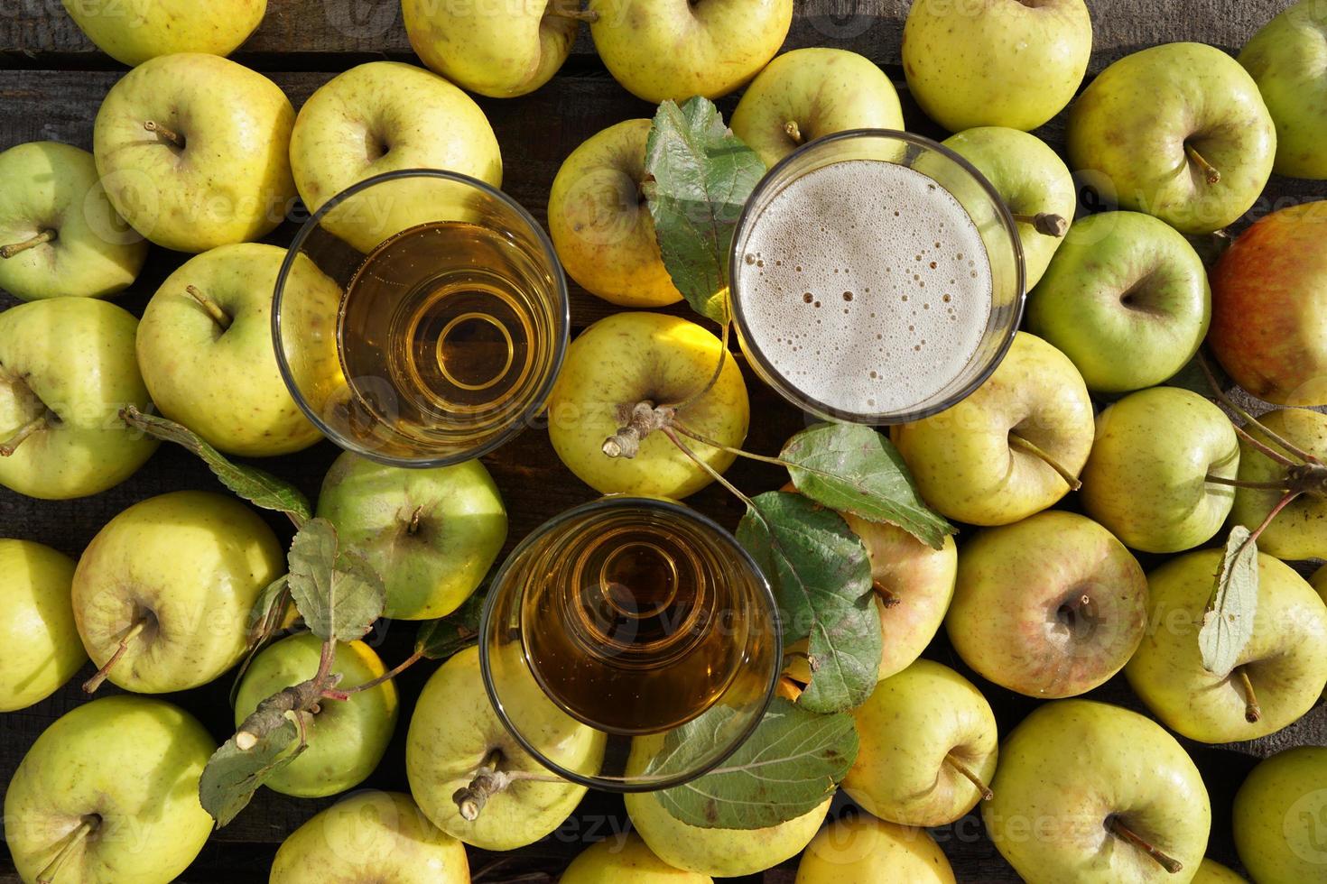 três copos de cidra de maçã e frutas amarelas na mesa. foto