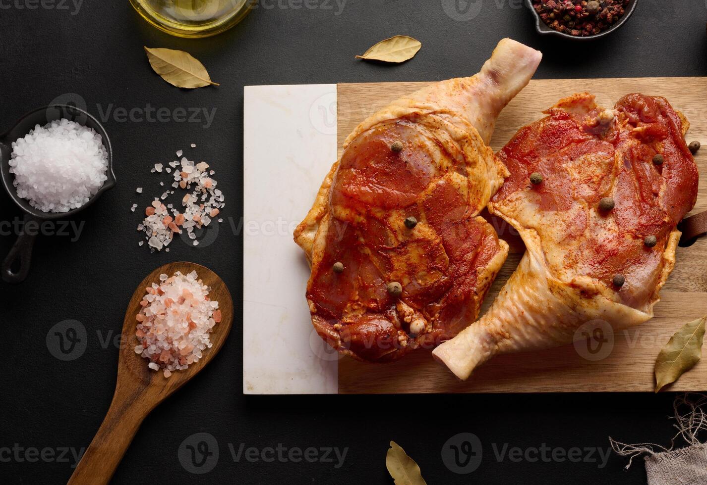 cru frango baquetas temperado em uma de madeira quadro, acompanhado de sal e Pimenta, visto a partir de a topo. foto