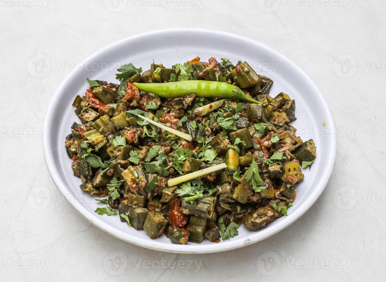 frito bhindi ou senhora dedo com cebola, ruivo, tomate e verde Pimenta servido dentro prato isolado em mesa topo Visão do indiano e paquistanês picante Comida foto