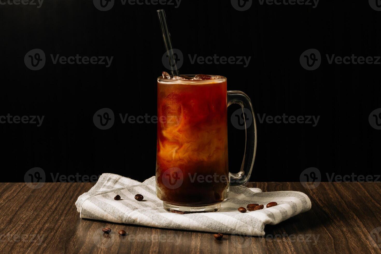 gelado café dentro uma alta vidro e café feijões, Sombrio concreto mesa frio verão beber sobre Sombrio de madeira fundo. foto