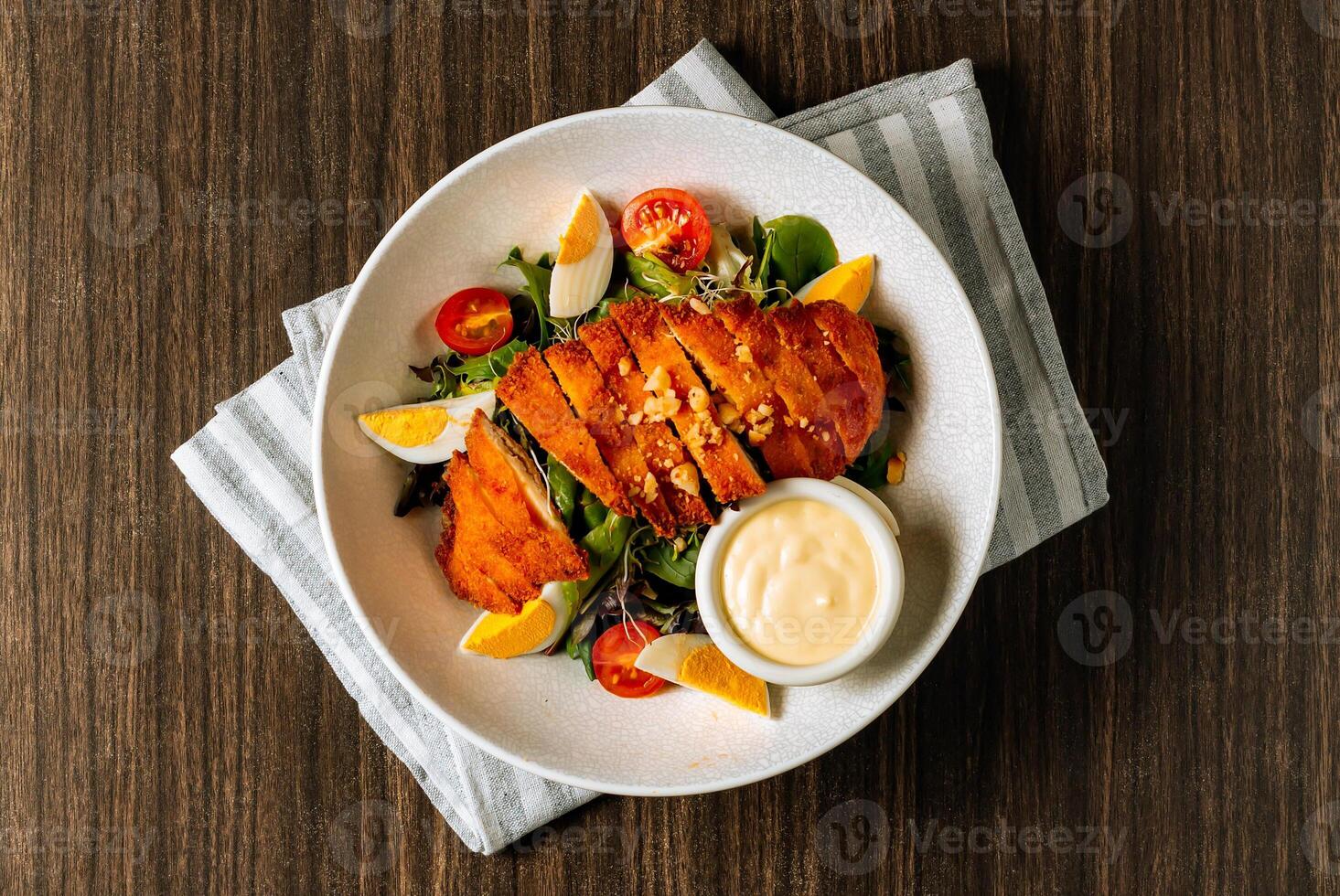 frango schnitzel servido com fresco salada, fervido ovo, tomate e maionese dentro branco tigela em Sombrio madeira fundo topo visualizar. foto