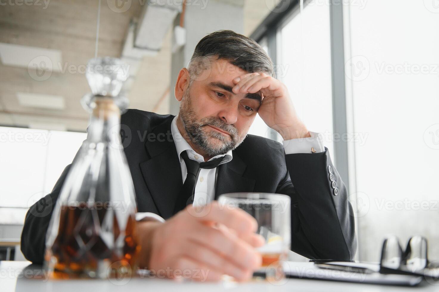 velho masculino empregado bebendo álcool às local de trabalho foto