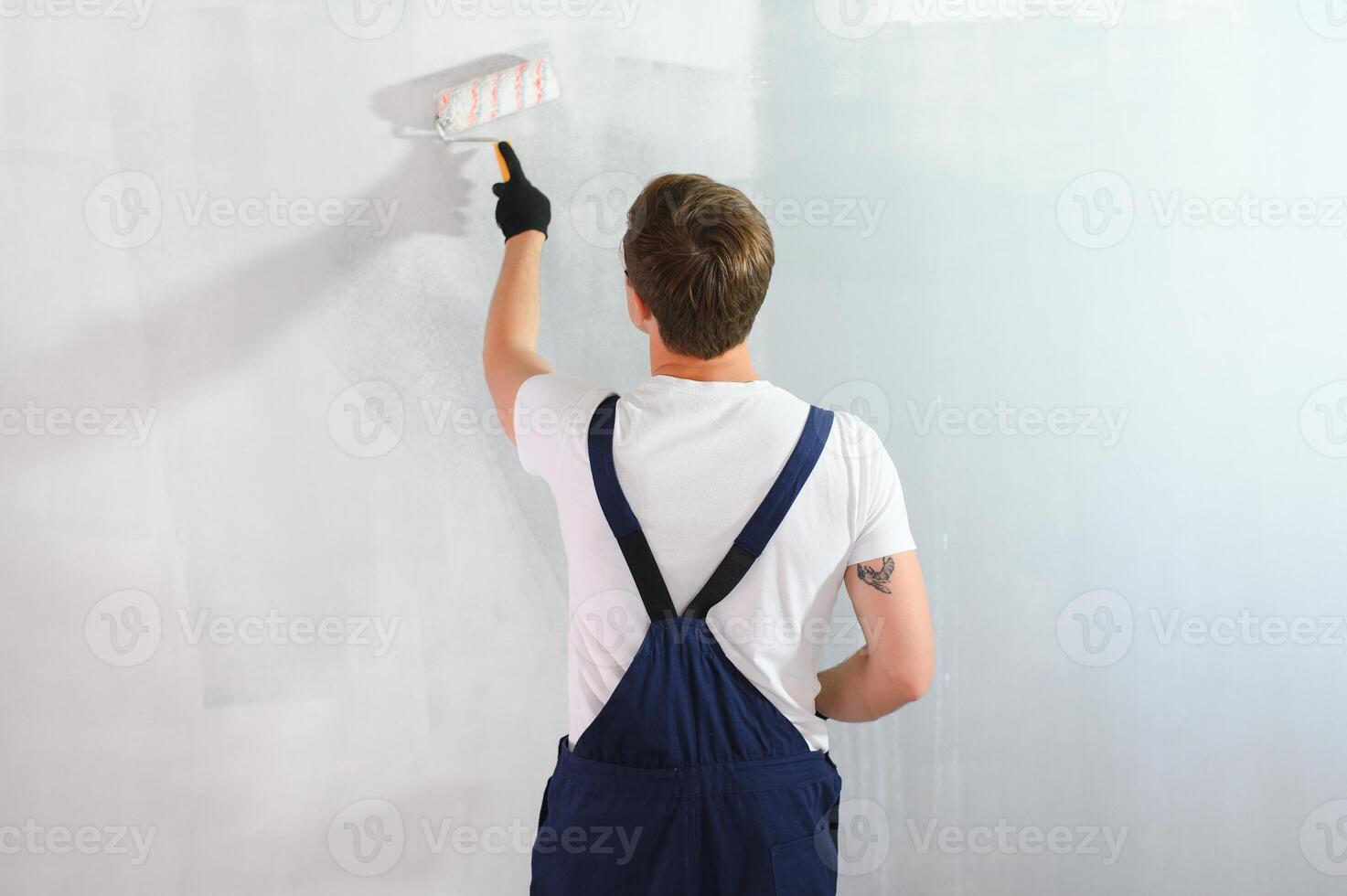 jovem trabalhador pintando parede no quarto foto