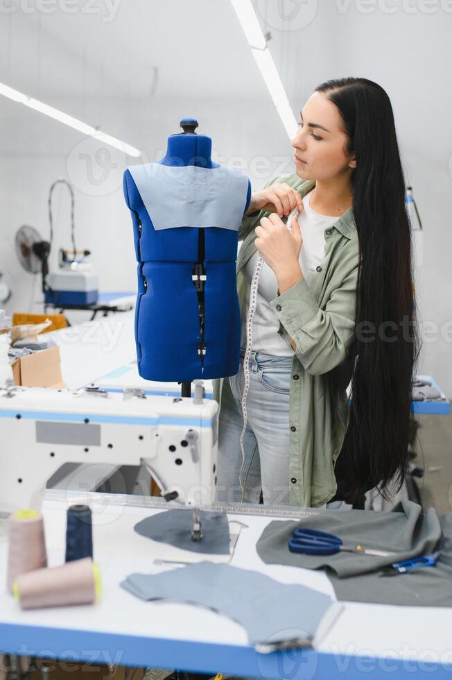 jovem mulher trabalhando Como costureira dentro roupas fábrica. foto