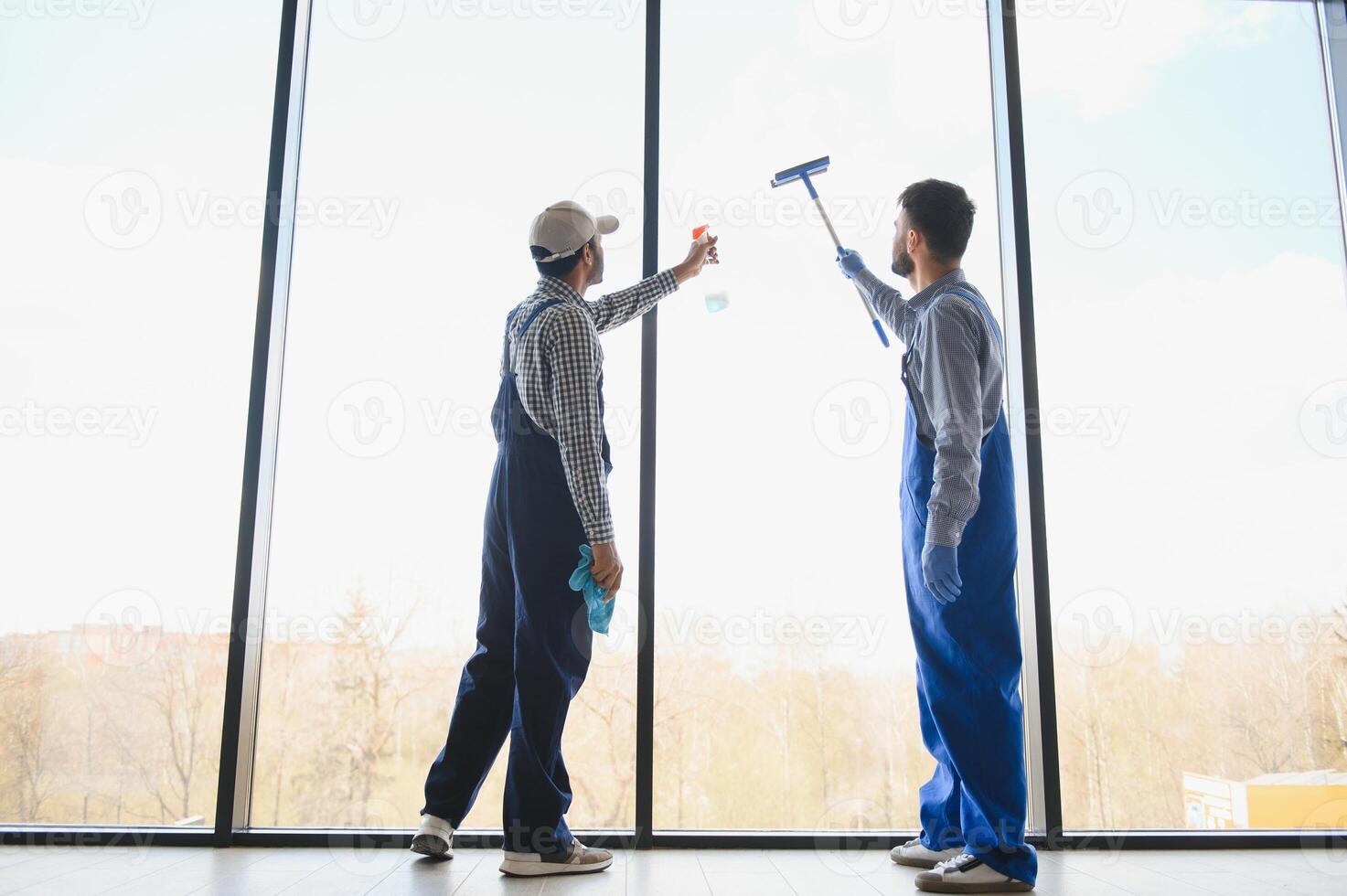 multiétnico profissional limpadores dentro uniforme lavando ampla janelas dentro escritório foto