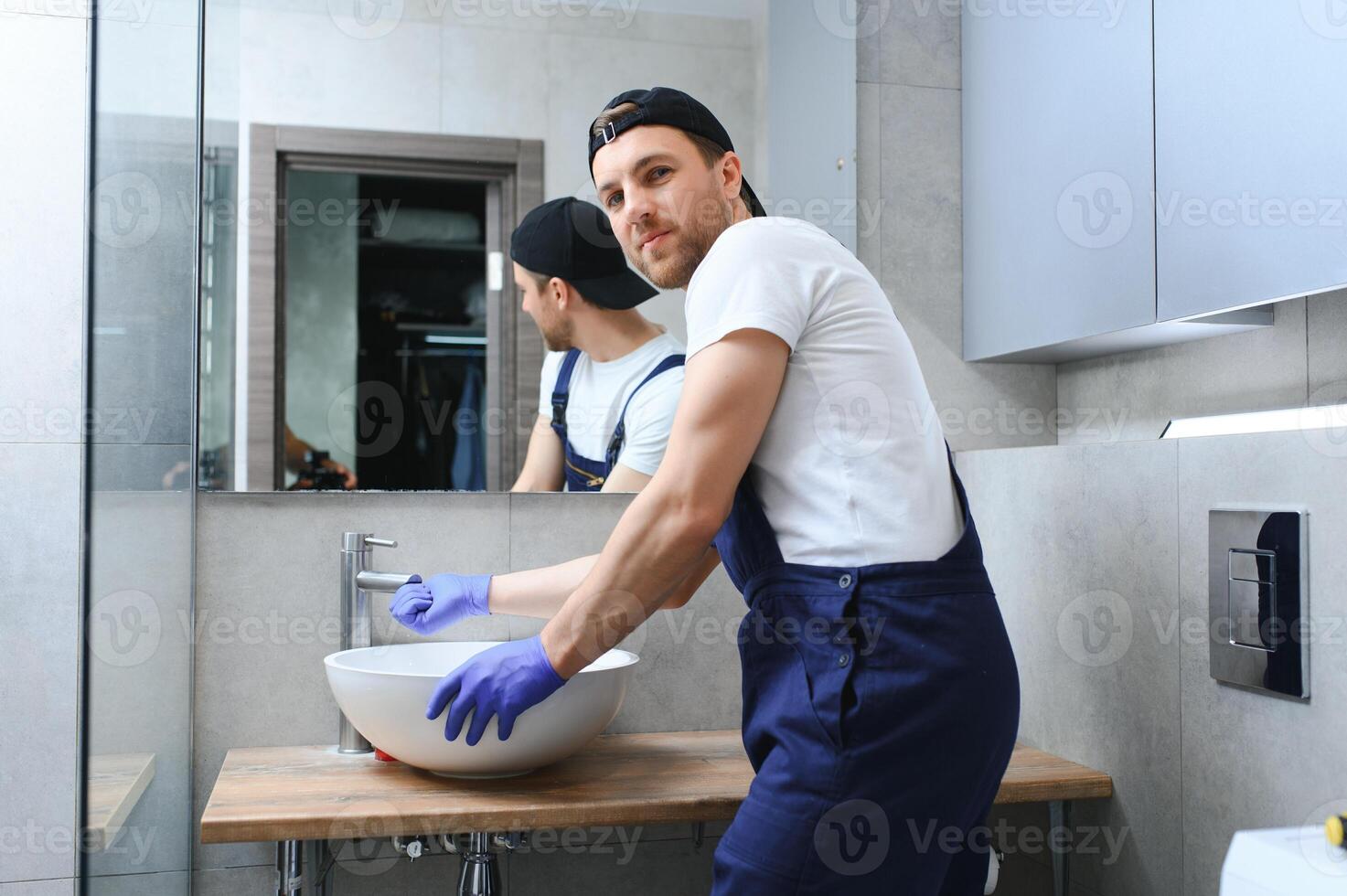 profissional encanador, masculino trabalhador dentro uniforme instalando Pia e água tubo dentro Novo apartamento. foto