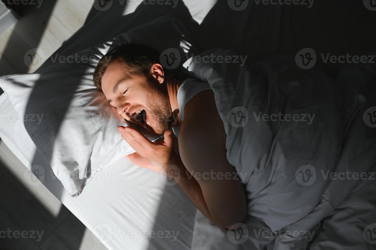 feliz jovem barbudo homem é relaxante em a cama às casa foto