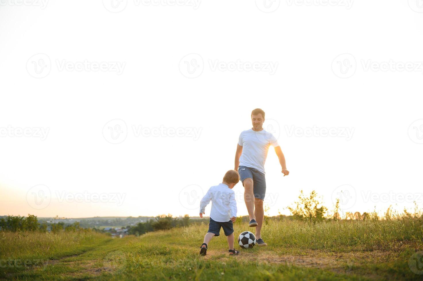 jovem pai com dele pequeno filho jogando futebol, do pai dia. foto