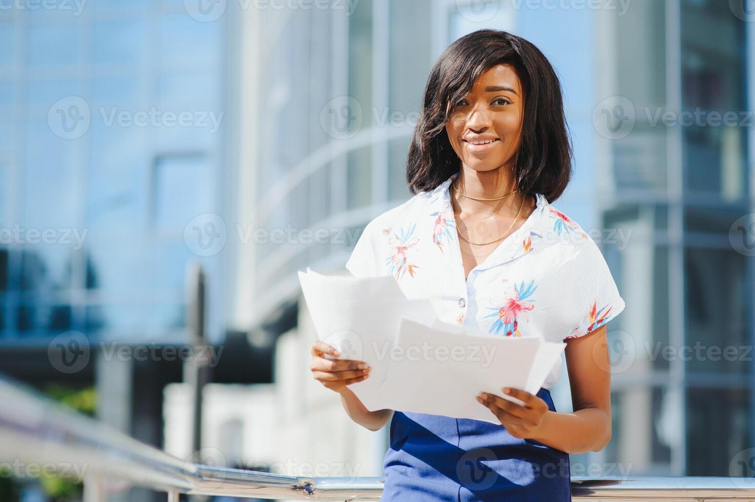 conteúdo formal africano americano mulher dentro terno em pé em calçada em rua e lendo papéis dentro Arquivo contra contemporâneo construção foto