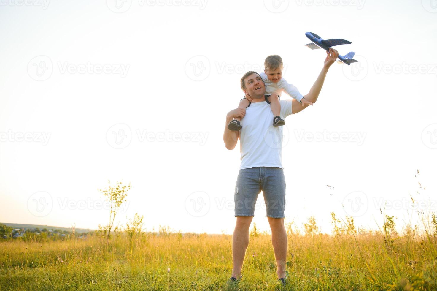 Papai com dele filho às pôr do sol dentro natureza. uma pai tocam com brinquedo aviões com dele filho às pôr do sol. do pai dia foto