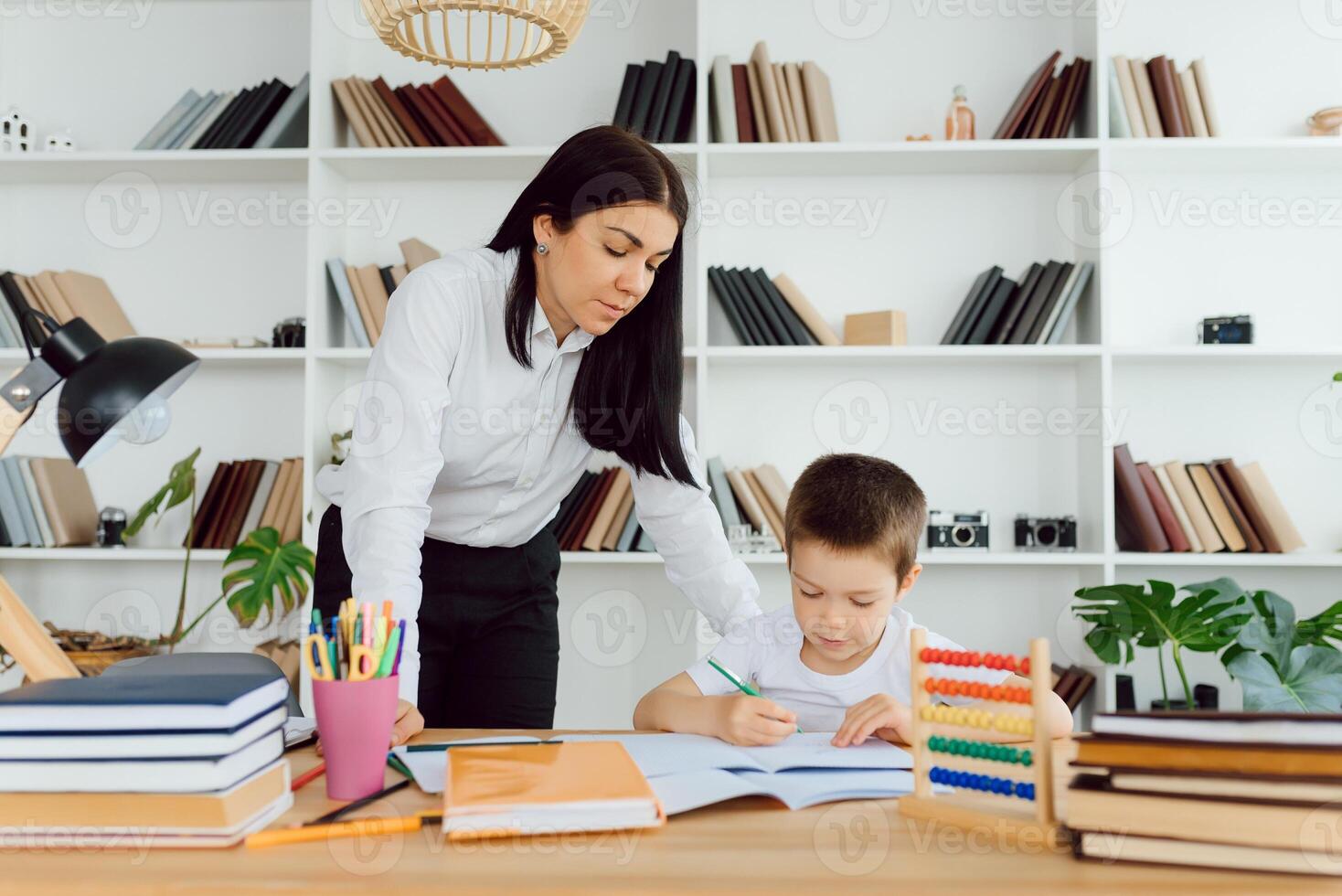 retrato de menino bonito no local de trabalho com seu tutor sentado por perto e dizendo algo foto