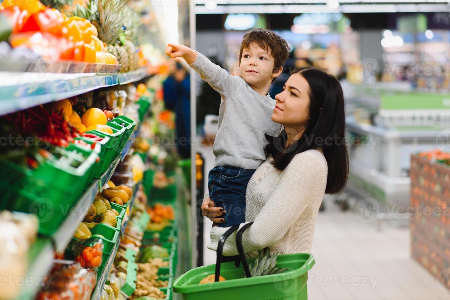 mulher e criança Garoto durante família compras com carrinho às supermercado foto