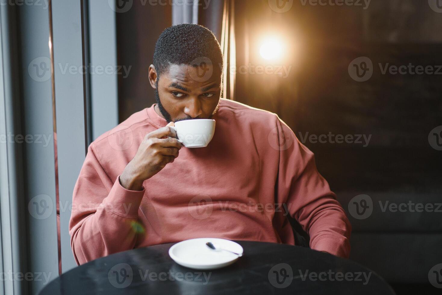 jovem bonito pele escura homem de negocios bebidas café dentro uma cafeteria foto