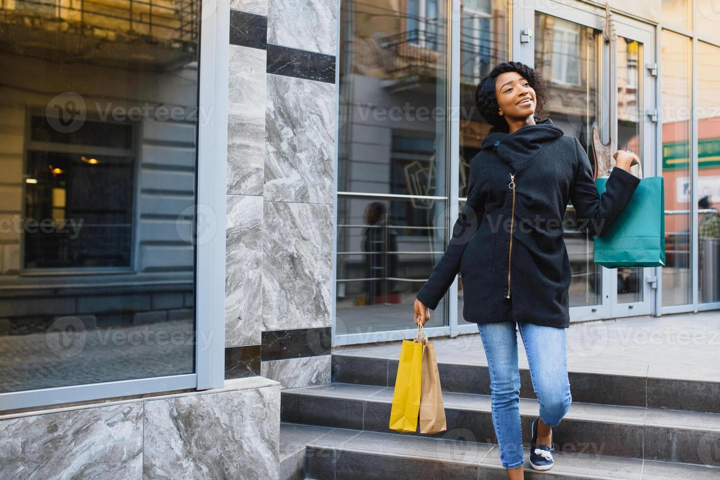 lindo encaracolado cabelos Afro-Americano mulher em pé dentro uma compras Shopping com colori compras bolsas dentro mãos. foto