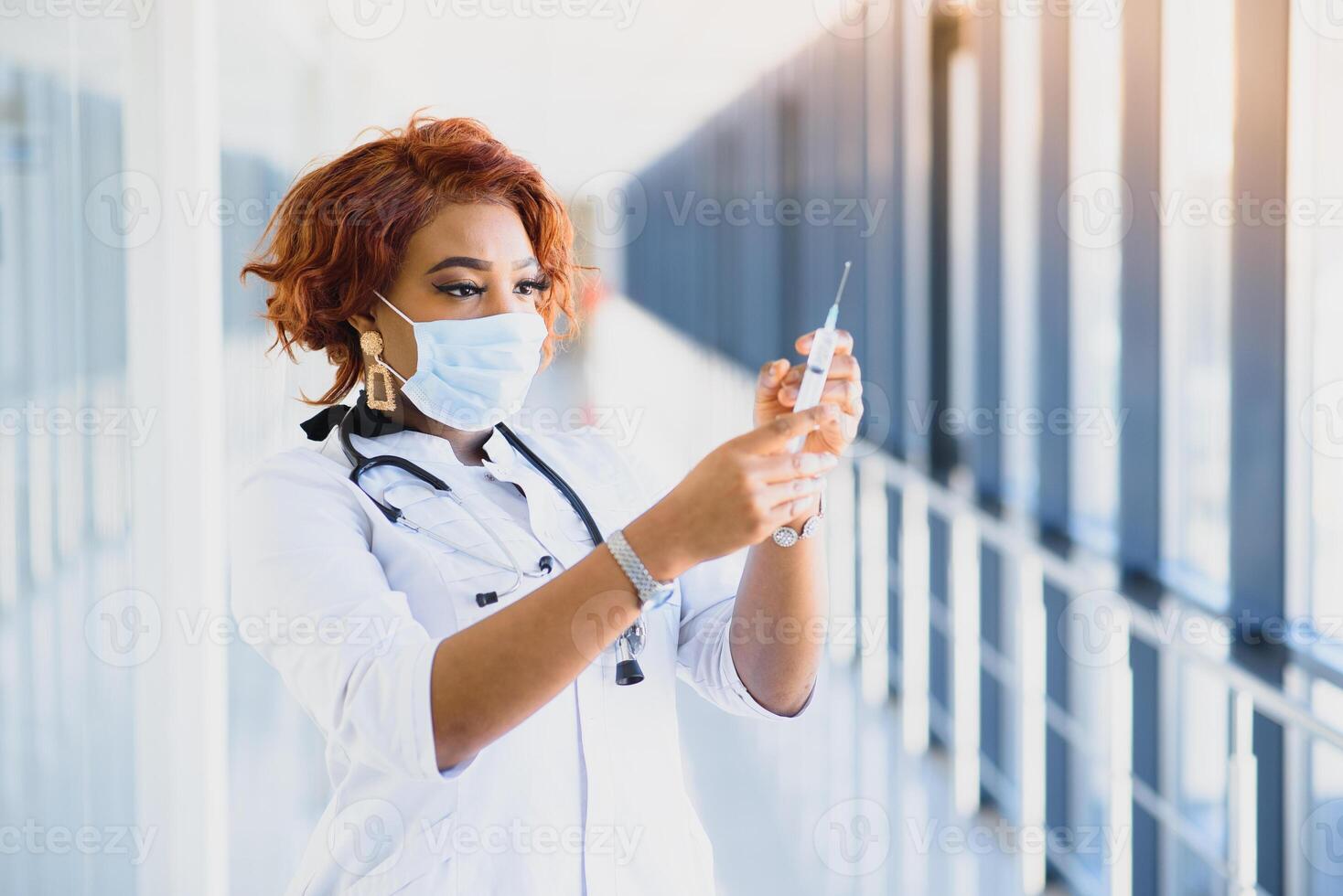 jovem sorridente africano americano médico dentro médico mascarar segurando uma seringa foto