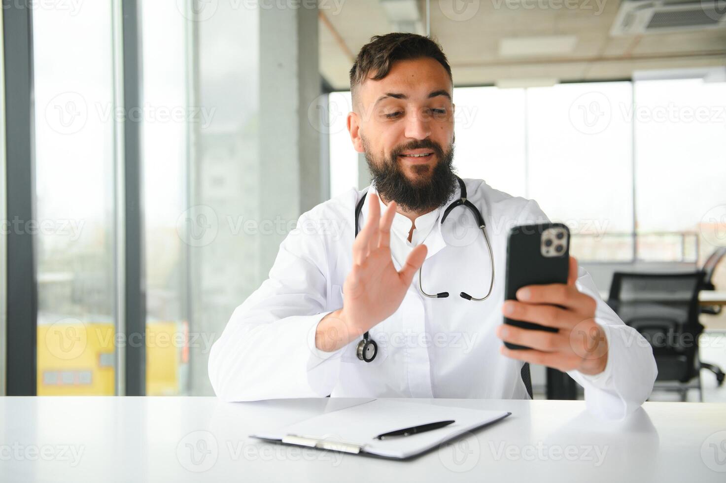 alegre jovem árabe homem médico tendo vídeo ligar com paciente foto