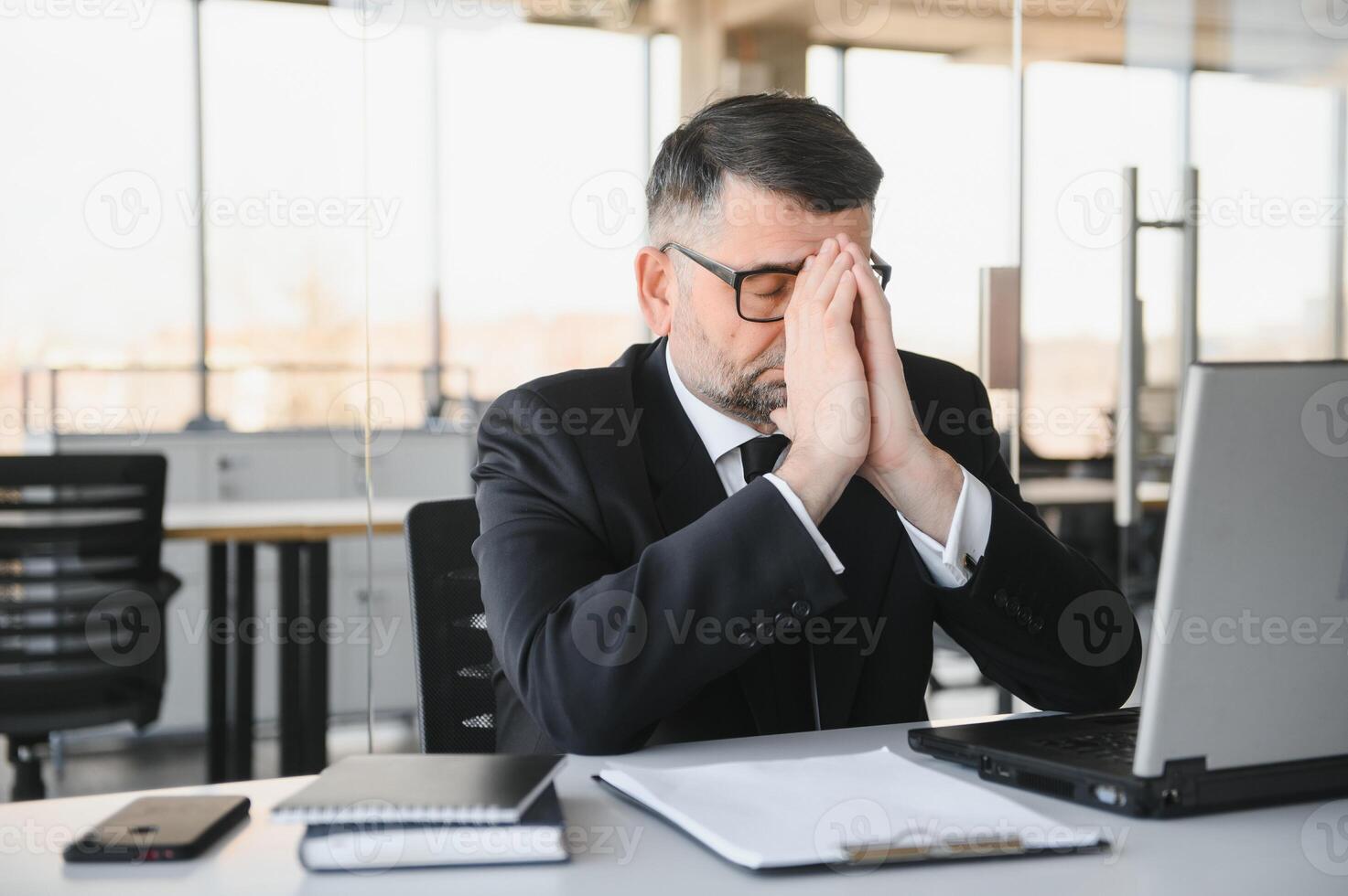 cansado estressado escritório trabalhador sentado às escrivaninha e pensamento, ele é fricção dele olhos e sentindo-me Exausta. foto